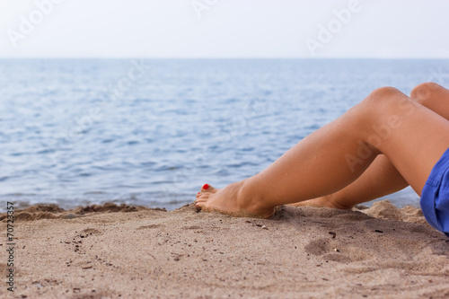 Legs of a young girl on a sandy beach © PhotoIris2021