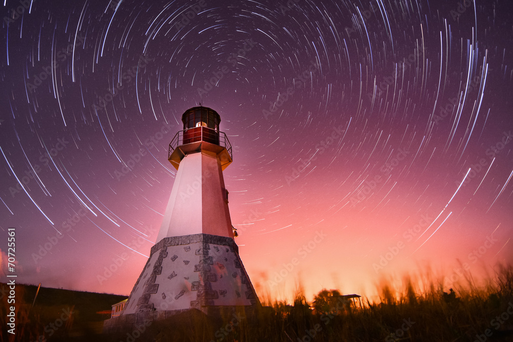Obraz premium lighthouse with night sky at background stars trails
