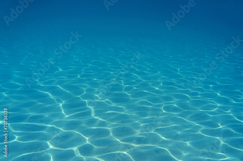 Ripples of sunlight underwater on sandy seabed photo