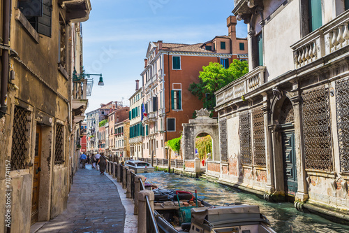 Narrow canal among old colorful brick houses in Venice