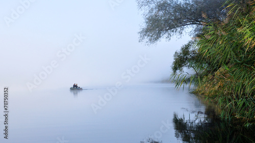 Fishing boat on a misty river in the morning 