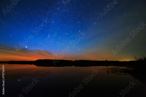 Morning dawn on a starry background sky reflected in the water o © lexuss