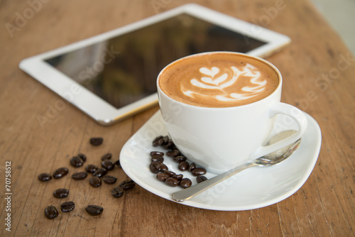 cup of coffee on table in cafe with tablet