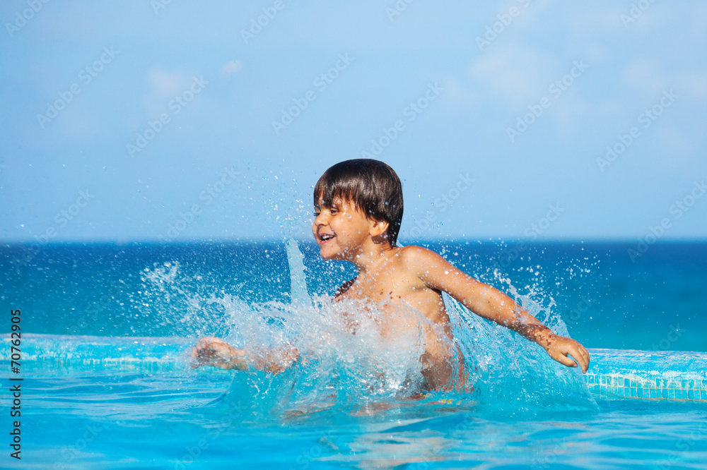 Happy boy splashing water around him in pool Happy boy splashing water around him in pool