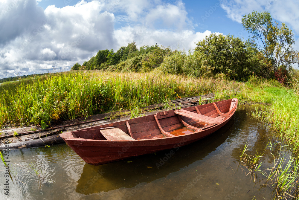 Old wooden boat at the lake in summer day