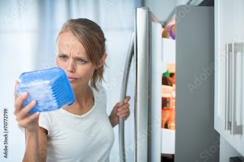 Bilde på lerret Is this still fine? Pretty, young woman in her kitchen