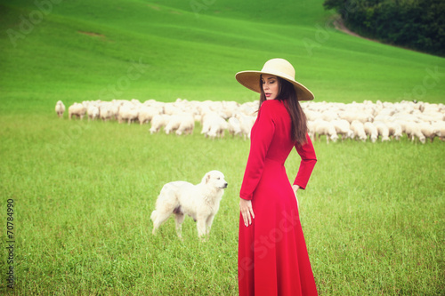 Beautiful woman in a field between the Tuscan sheep