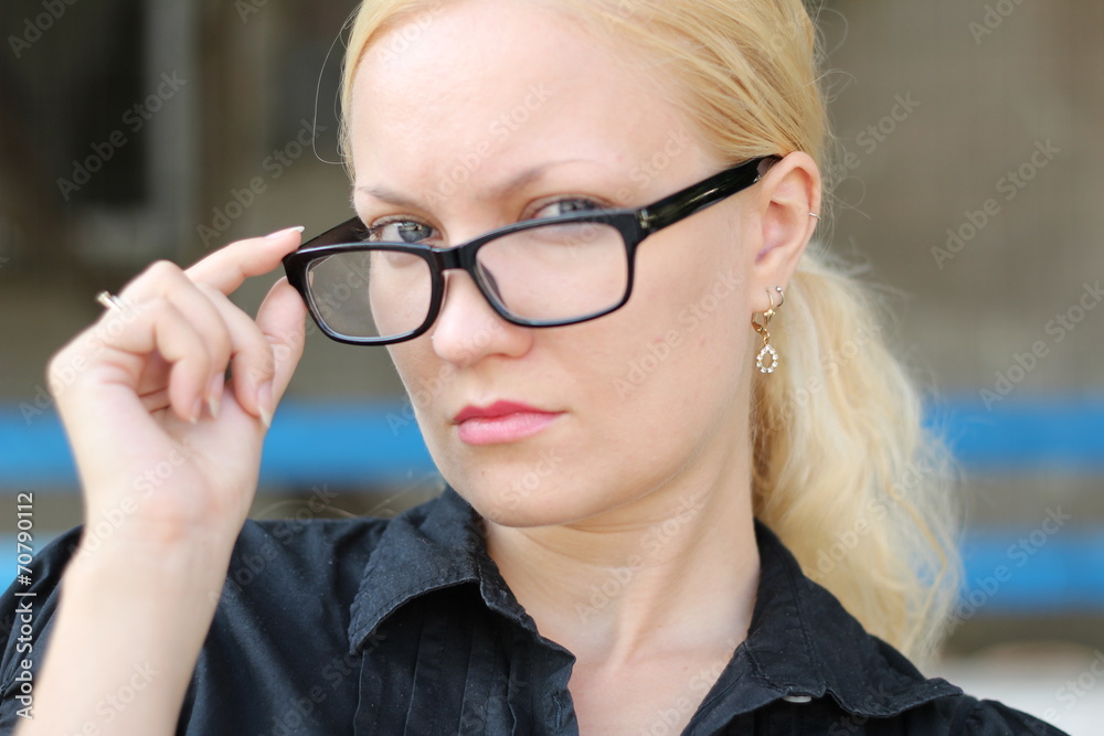 Blond businesswoman outside, holding her glasses