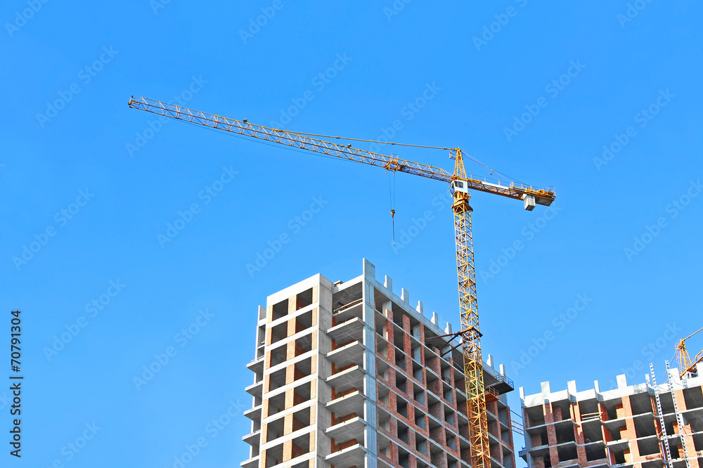 Crane and building construction site against blue sky