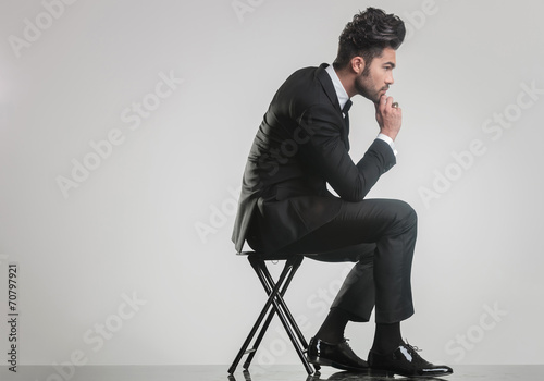 elegant young man sitting on a stool and thinking