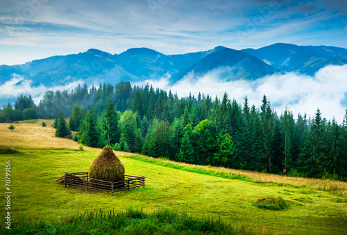 Amazing mountain landscape with fog and a haystack photo