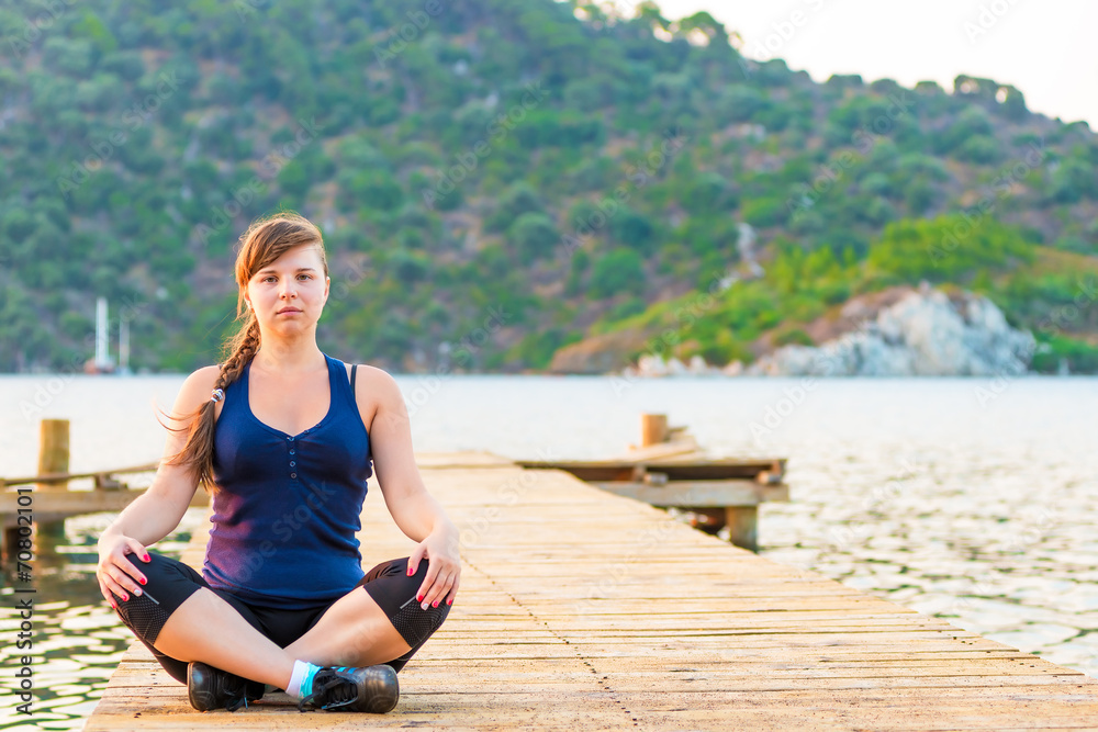 portrait of a girl in a lotus position on the pier
