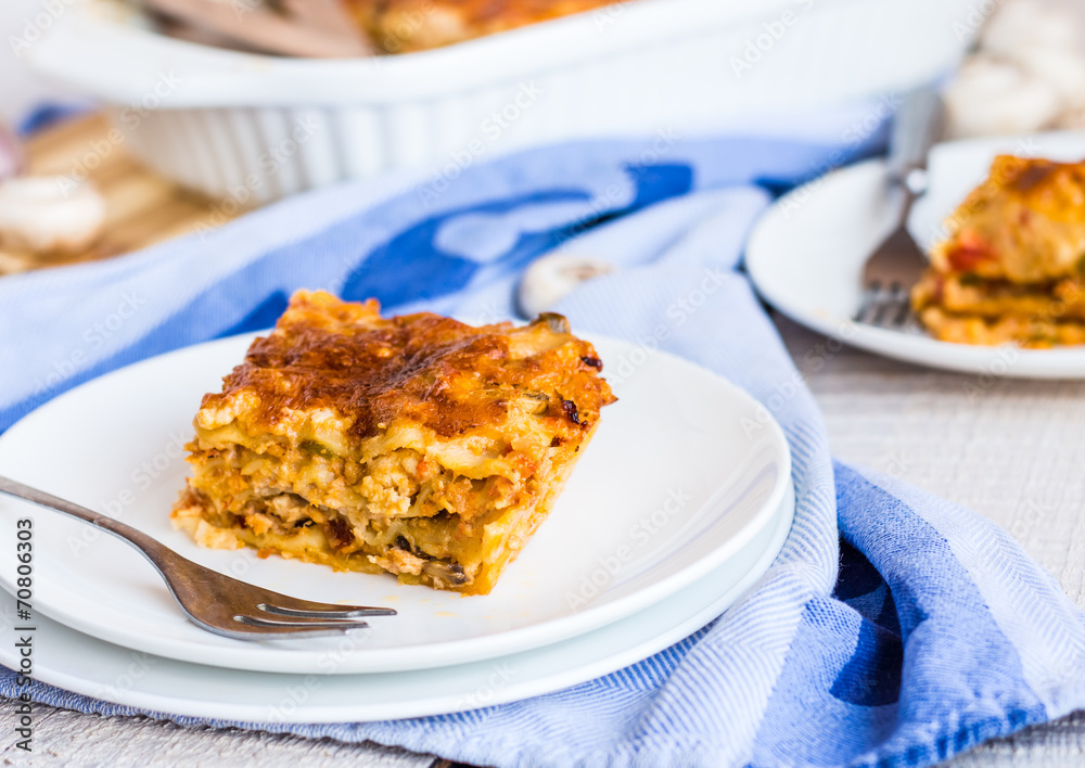 eating a piece of meat lasagna with mushrooms, blue towel