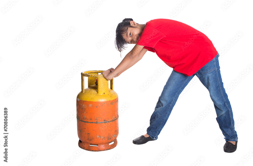 Young Asian girl moving an old cooking gas propane cylinder Young Asian girl moving an old cooking gas propane cylinder