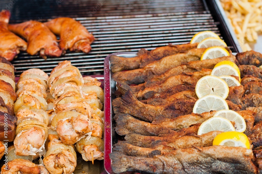 Fresh fried fish with lemon slice and grilled meat in market