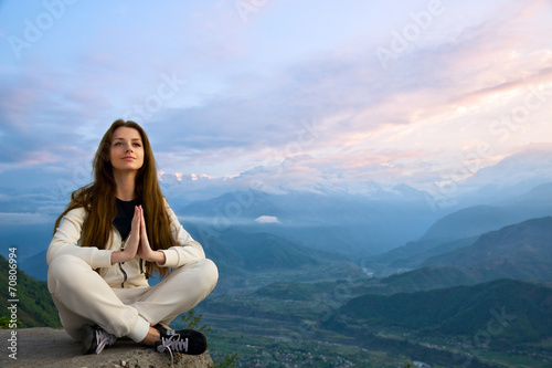 Young beautiful woman meditating in The Himalayas at sunrise