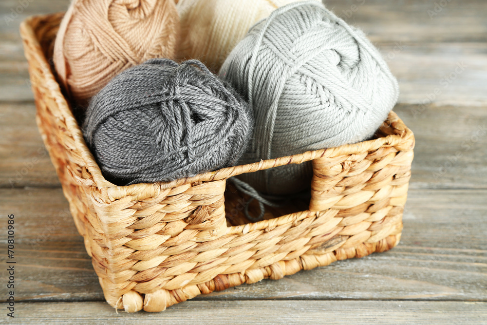 Obraz premium Knitting yarn in basket, on wooden background