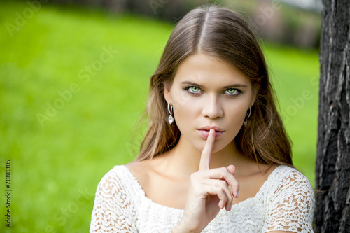 Woman has put forefinger to lips as sign of silence