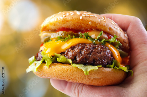 Hand holding warm hamburger in outdoors