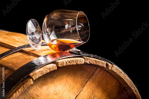 Glass of cognac on the old wooden barrel