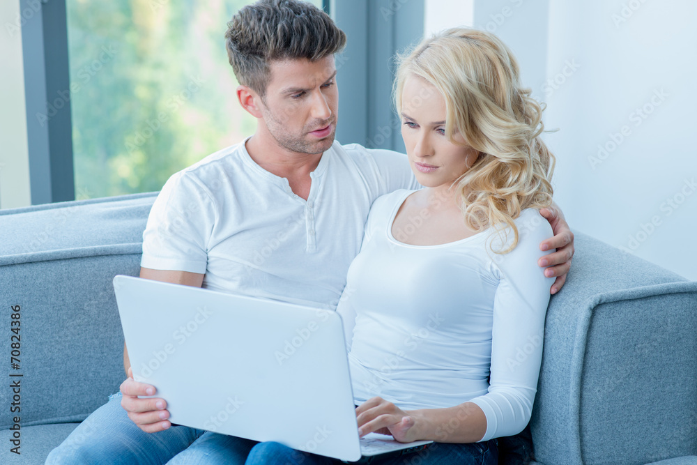 Concerned young couple using a laptop computer Concerned young couple using a laptop computer