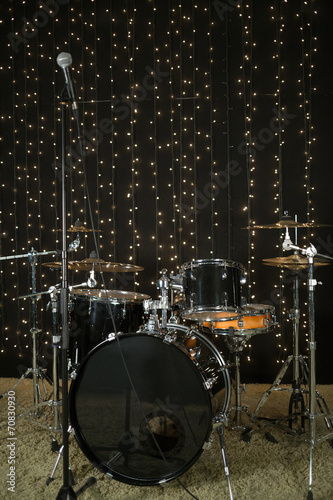 Drum set with microphones and cymbals in room with garland.