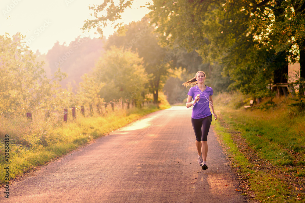 Sportliche Frau läuft am Morgen auf einer ländlichen Straße