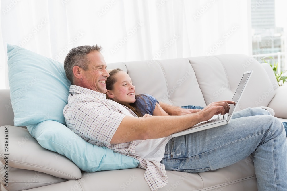 Father with daughter relaxing on the couch using laptop Father with daughter relaxing on the couch using laptop