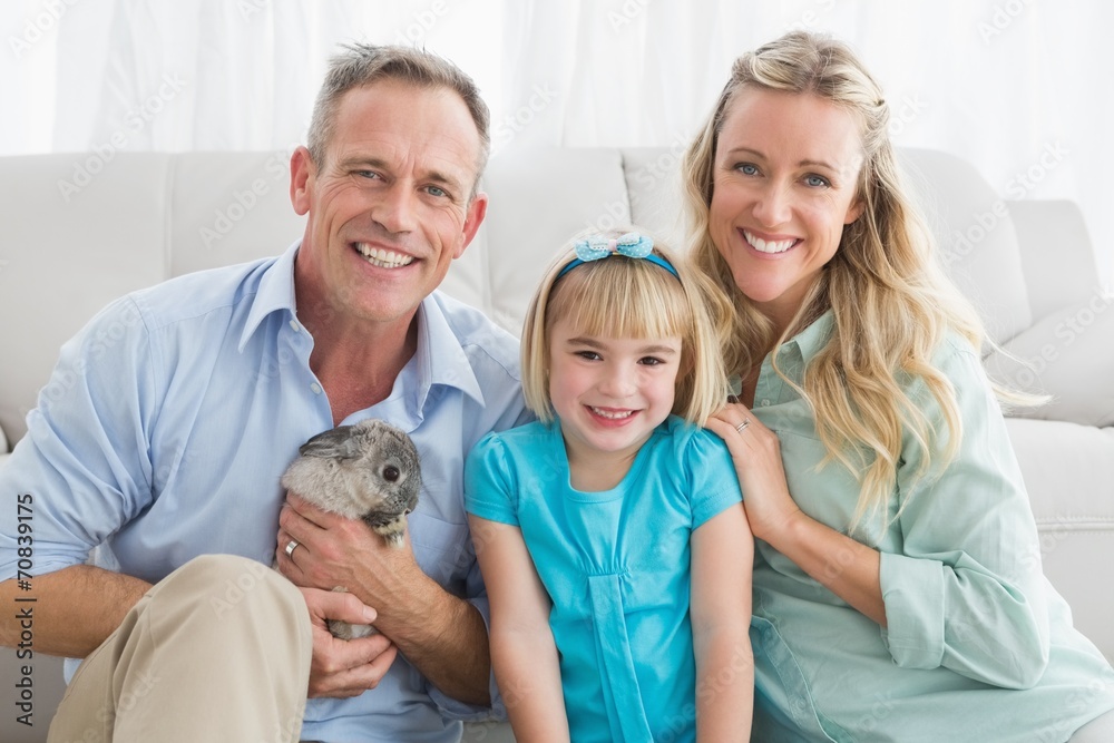 Smiling parents and daughter sitting with rabbit together