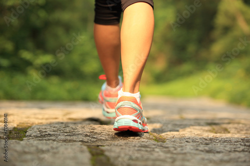 young fitness woman legs running at forest trail 