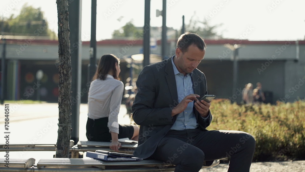 Young businessman using smartphone on bench in the city Young businessman using smartphone on bench in the city