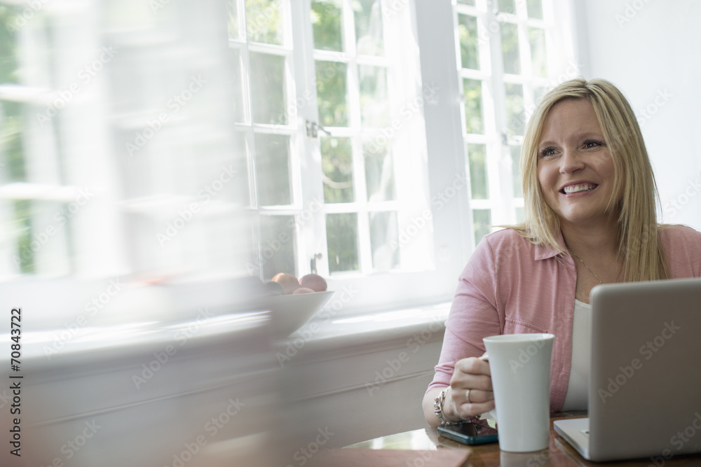 A woman using a laptop at a table, working at home. A woman using a laptop at a table, working at home.