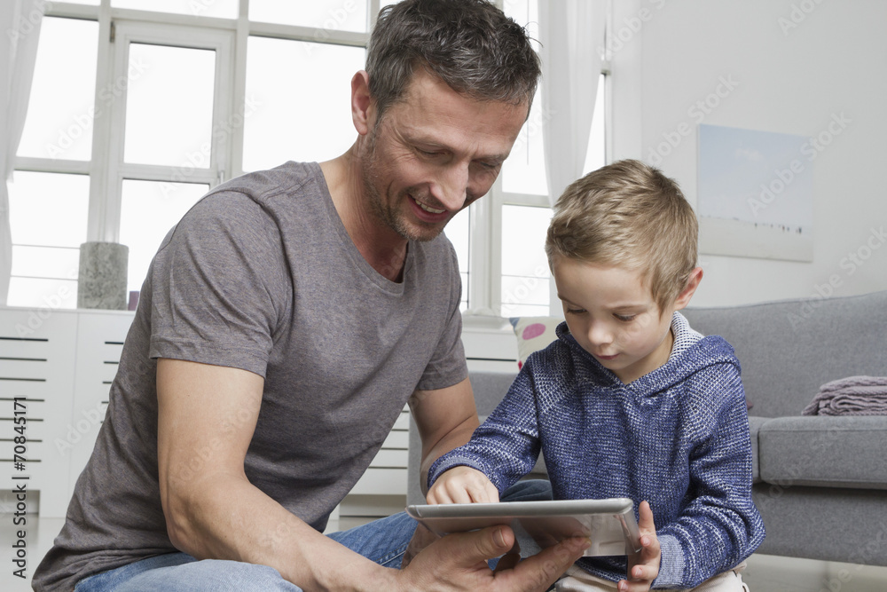 Father and son using tablet computer in living room Father and son using tablet computer in living room