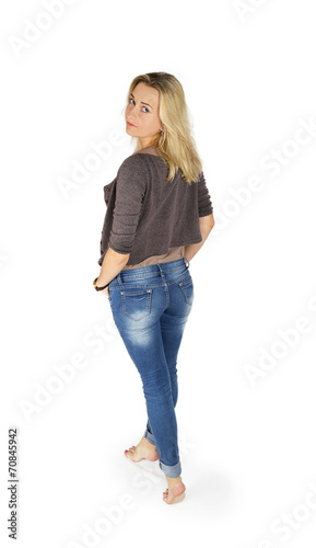 Young attractive woman in blue jeans standing from the back and
