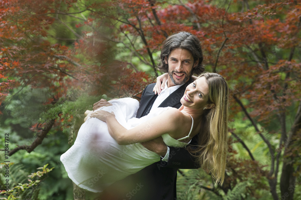 Groom carrying bride in garden Groom carrying bride in garden