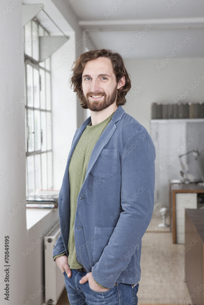 Portrait of smiling young man standing in an office Portrait of smiling young man standing in an office