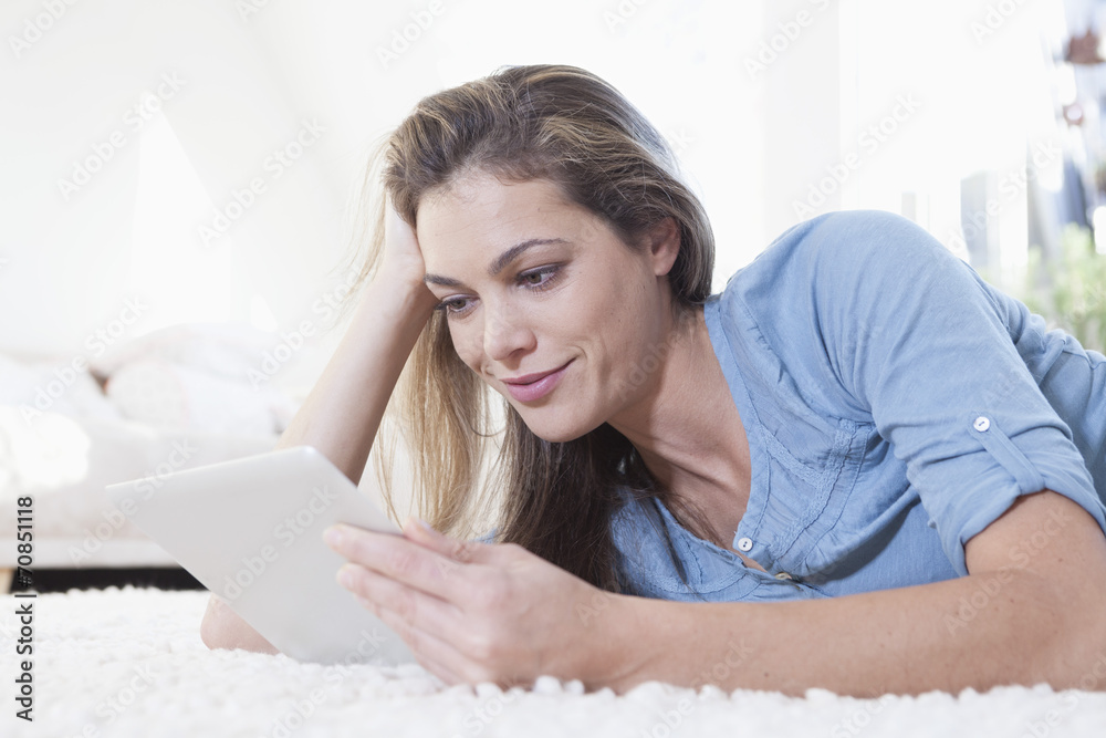 Portrait of woman lying on a carpet using tablet computer Portrait of woman lying on a carpet using tablet computer