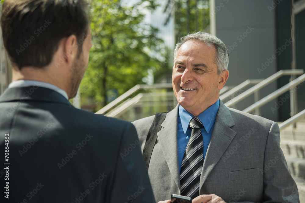 Two smiling businessmen outside office building Two smiling businessmen outside office building