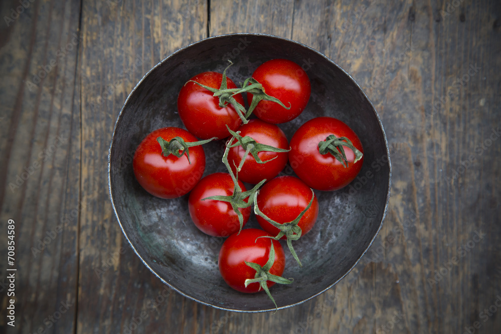 Bowl with cherry tomatoes on wooden table, elevated view Bowl with cherry tomatoes on wooden table, elevated view