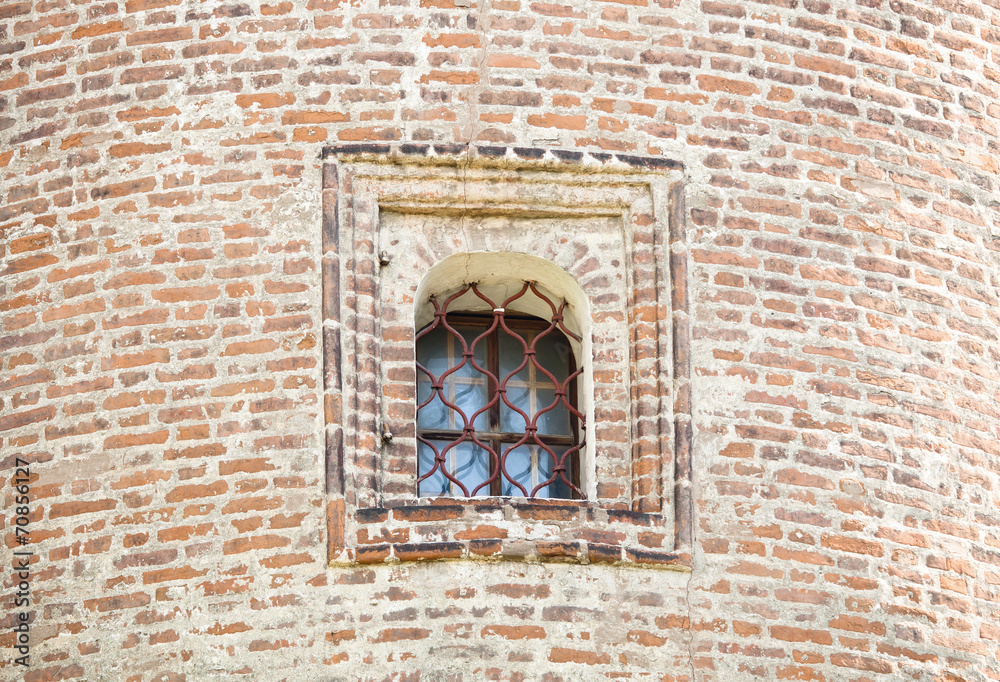 Obraz premium window with forged bars in the historic tower built of red brick