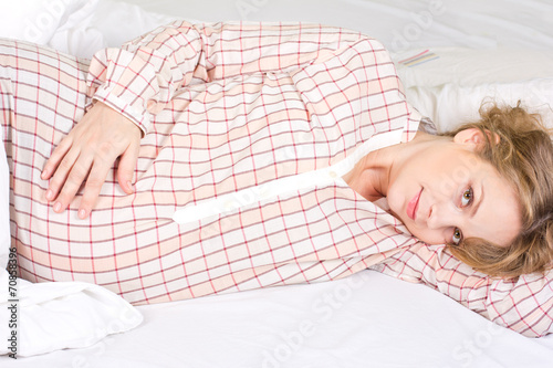 Beautiful pregnant blonde basking in the white bed photo