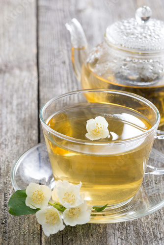 kettle and a cup of green tea with jasmine on wooden table