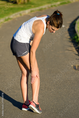 Female athlete suffering a calf muscle cramp injury while runnin
