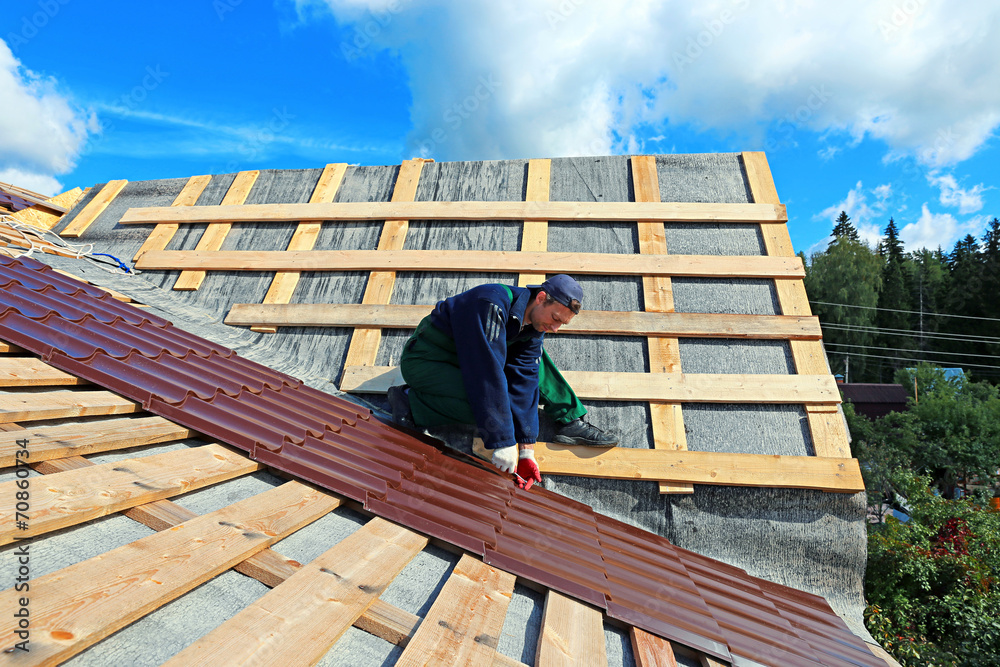 Worker puts the metal tiles on the roof