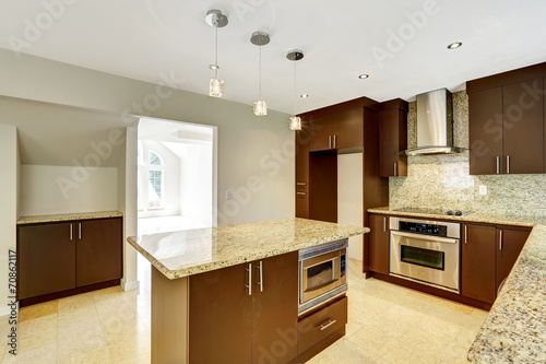 Modern kitchen room with matte brown cabinets and granite trim.