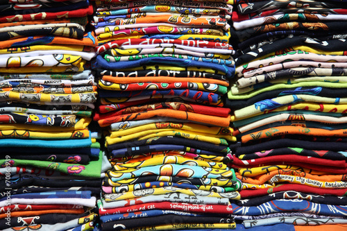 magliette di cotone impilate l'una sull'altra pronte per essere vendute ai turisti. Ottima fattura, colori brillanti e vivaci per prodotti per vestire bambini, adulti e anche anziani photo