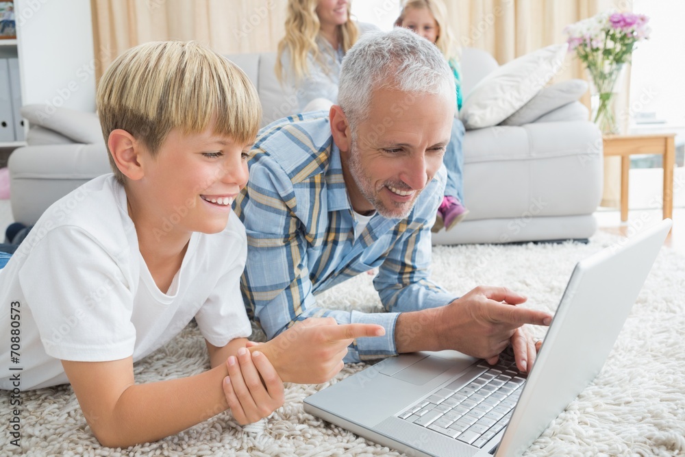 Obraz premium Father and son using laptop on the floor