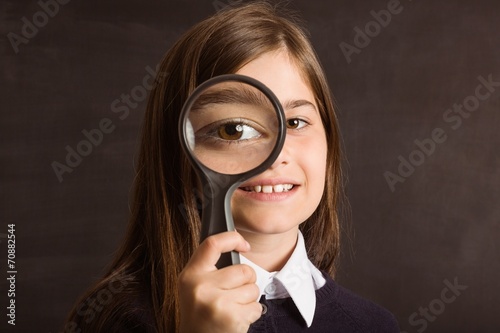 Cute pupil looking through magnifying glass