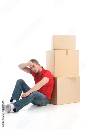 male sitting on floor tired of moving boxes.