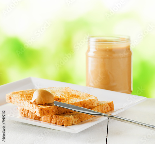 Jar of peanut butter and toasts on nature background